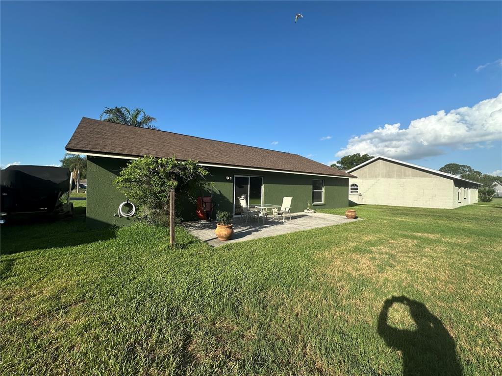 The exterior of a green house features a concrete patio, sliding glass doors, and lawn — 3084 THOROUGHBRED LOOP W, LAKELAND, FL