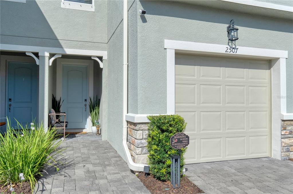 The exterior of a home features a light-colored garage, a front entryway, and stone accents — 2507 ARBOR WIND DRIVE, LUTZ, FL