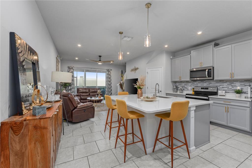 An open-concept kitchen and living area features gray cabinetry, a white island, and tile flooring — 2507 ARBOR WIND DRIVE, LUTZ, FL