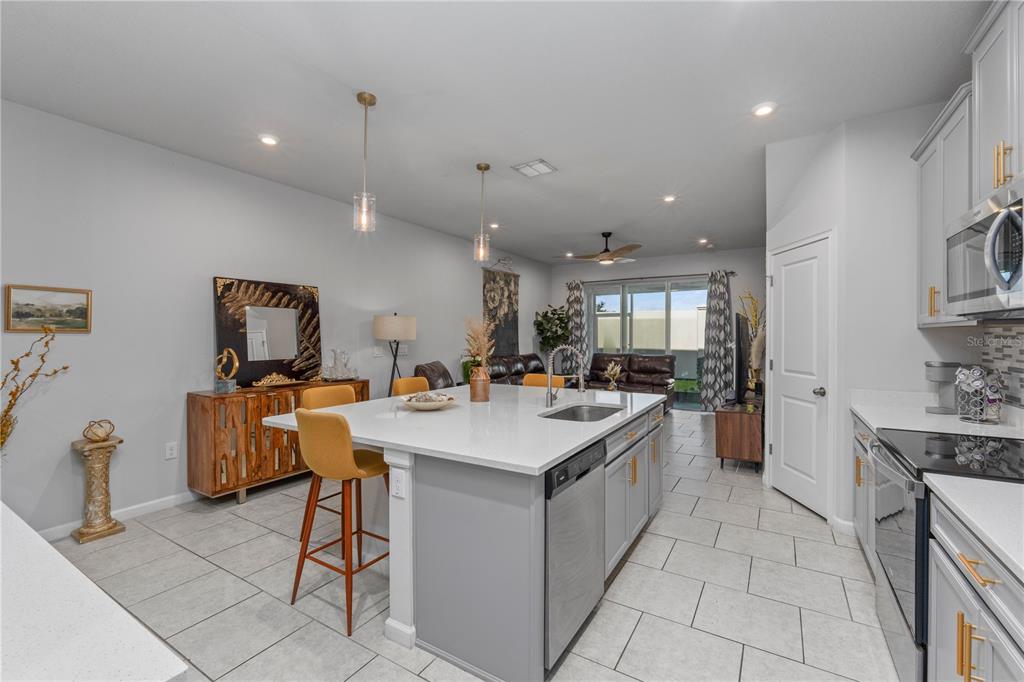 A kitchen with a large white island, grey cabinets, and tile flooring opens to a living area — 2507 ARBOR WIND DRIVE, LUTZ, FL