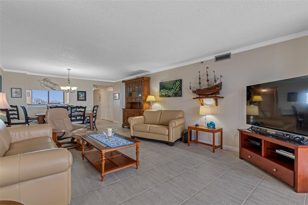 A living room with beige leather furniture, a wooden coffee table, and a model ship — 19111 VISTA BAY DRIVE UNIT 612, INDIAN SHORES, FL