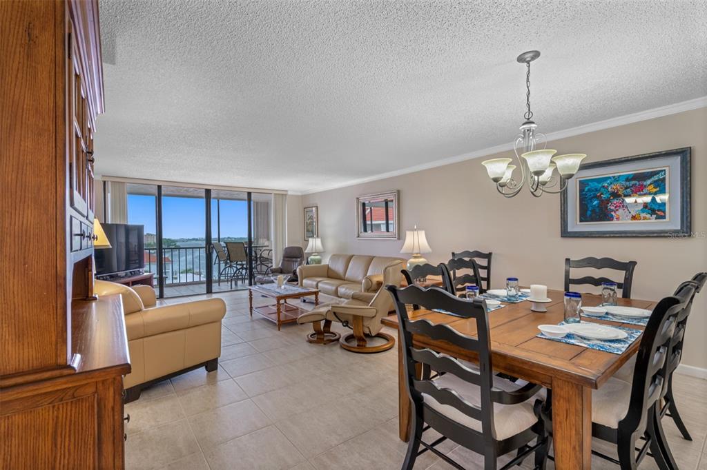An open-concept living and dining area with tile floors, a balcony, and water views — 19111 VISTA BAY DRIVE UNIT 612, INDIAN SHORES, FL