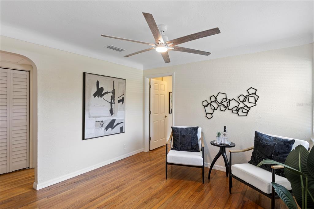 A room with hardwood floors, two chairs, a small table, wall art, and a ceiling fan — 417 HAMPTON AVENUE NE, ST PETERSBURG, FL