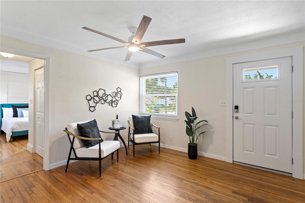 A living area features hardwood floors, two chairs, a ceiling fan, and a front door — 417 HAMPTON AVENUE NE, ST PETERSBURG, FL