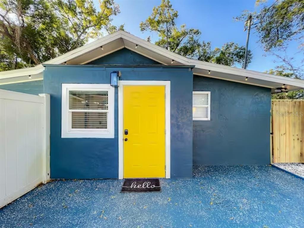 A blue exterior wall features a bright yellow front door and a white-framed window — 2008 PAGE AVE UNIT 2, ORLANDO, FL