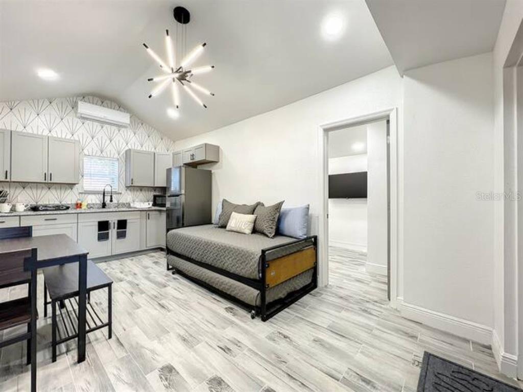 A studio apartment featuring a kitchenette, a daybed, and light wood-look tile flooring — 2008 PAGE AVE UNIT 2, ORLANDO, FL