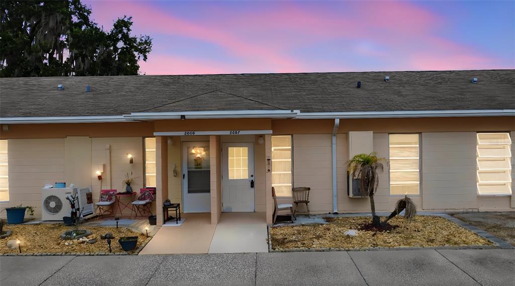 A single-story duplex building with two front doors, beige siding, and a gravel front yard — 2607 CLUB CIRCLE UNIT 2607, LAKE WALES, FL
