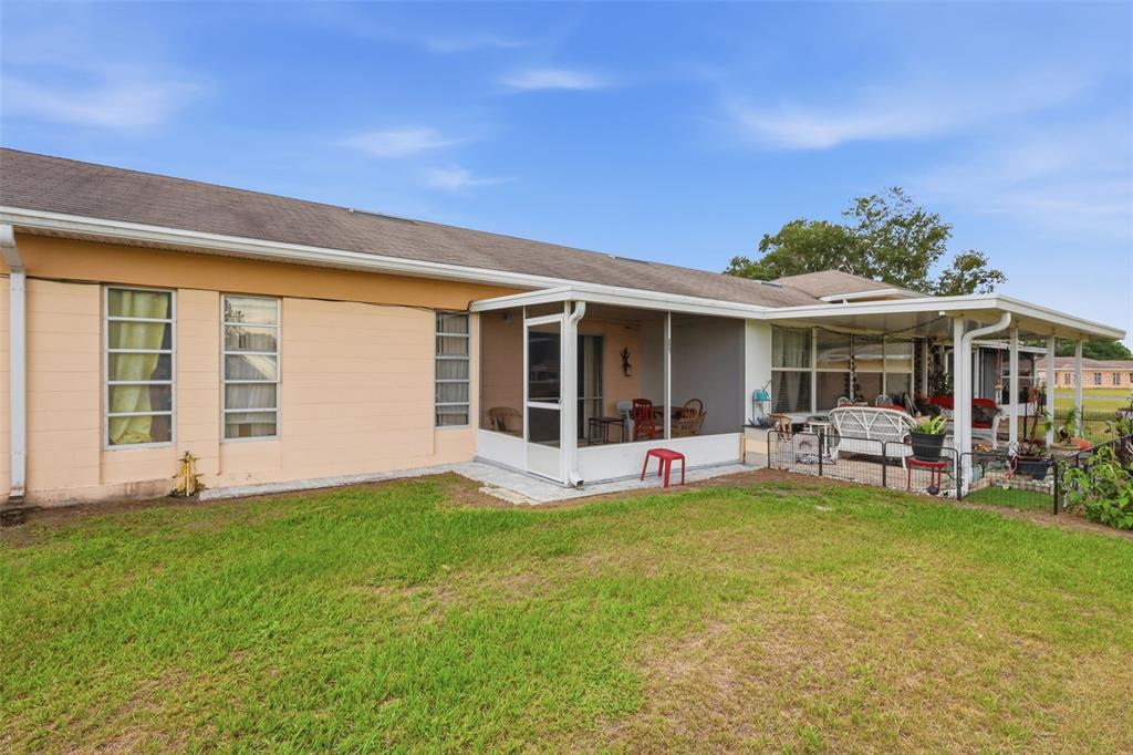 The exterior of a peach-colored house features a screened-in porch and a covered patio — 2607 CLUB CIRCLE UNIT 2607, LAKE WALES, FL