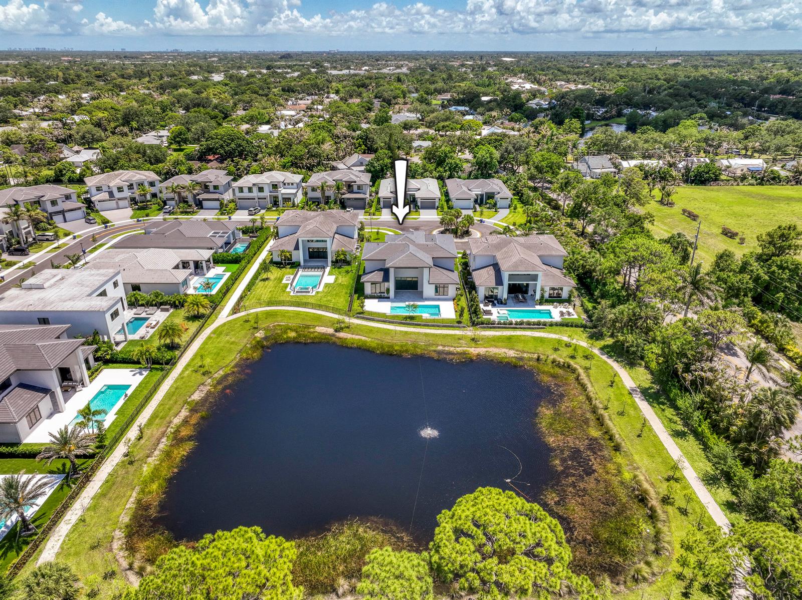 An aerial view shows a residential neighborhood with houses featuring swimming pools near a pond — 18409 Symphony Court, Jupiter FL 33458, JUPITER, FL