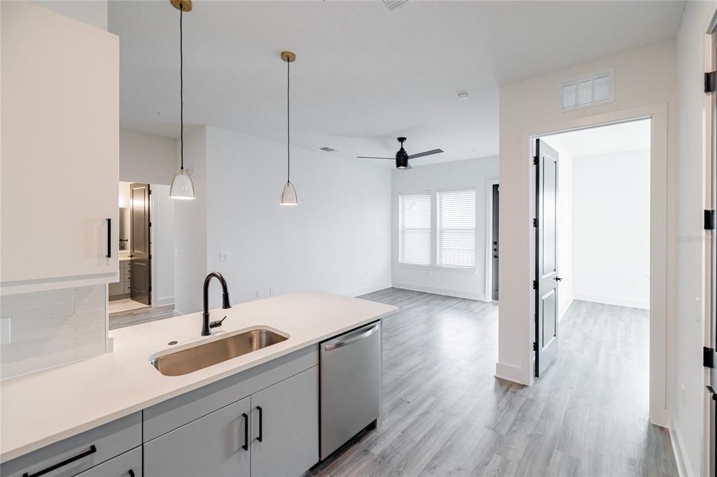 A kitchen island with a sink and dishwasher overlooks a living area with light flooring — 1420 LAKEFRONT DRIVE UNIT 3105, SARASOTA, FL