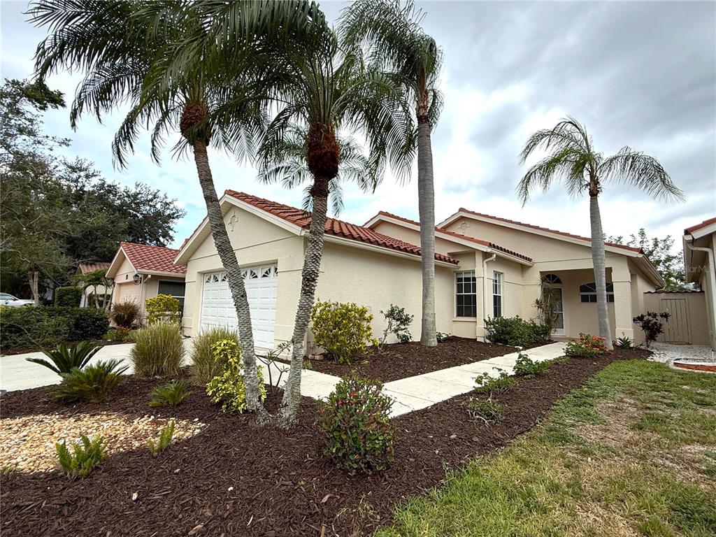 A single-story house with a white stucco exterior, red tile roof, and several palm trees — 4304 MARCOTT CIRCLE, SARASOTA, FL