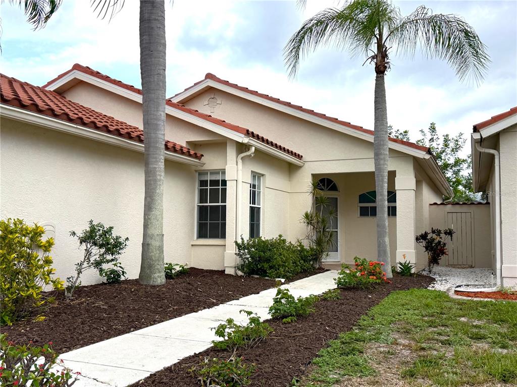 A single-story house with a tiled roof, palm trees, and a concrete walkway — 4304 MARCOTT CIRCLE, SARASOTA, FL