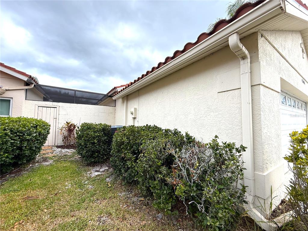A side view of a beige stucco house with a tiled roof and landscaping — 4304 MARCOTT CIRCLE, SARASOTA, FL