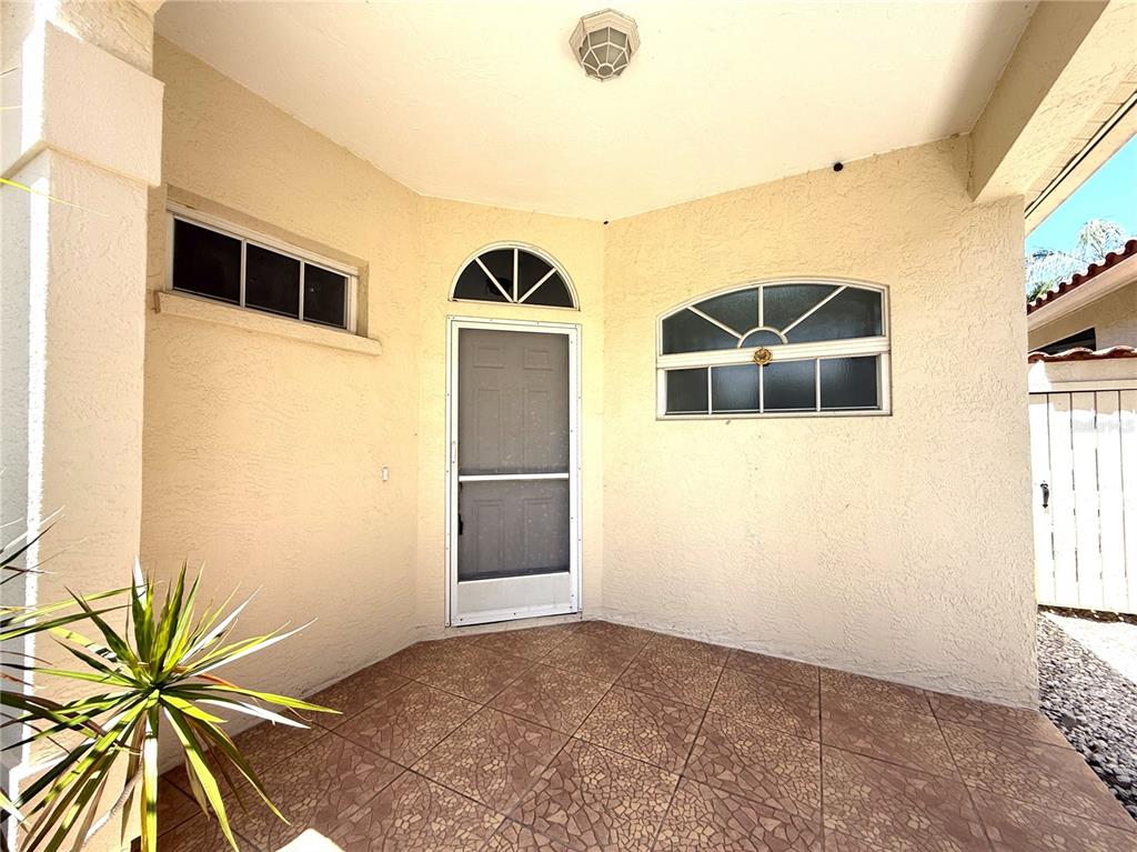 A covered entryway features tiled flooring, a screen door, and two windows with arched tops — 4304 MARCOTT CIRCLE, SARASOTA, FL