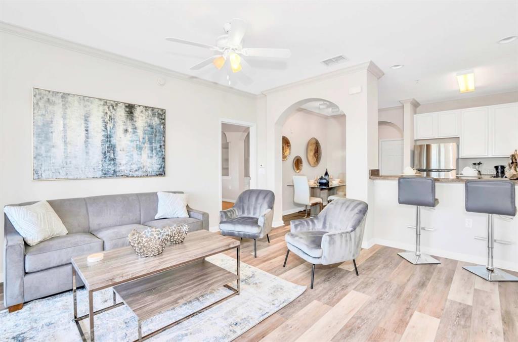 A living room with gray furniture, a wood coffee table, and an open kitchen area — 14200 AVALON ROAD UNIT 411, WINTER GARDEN, FL