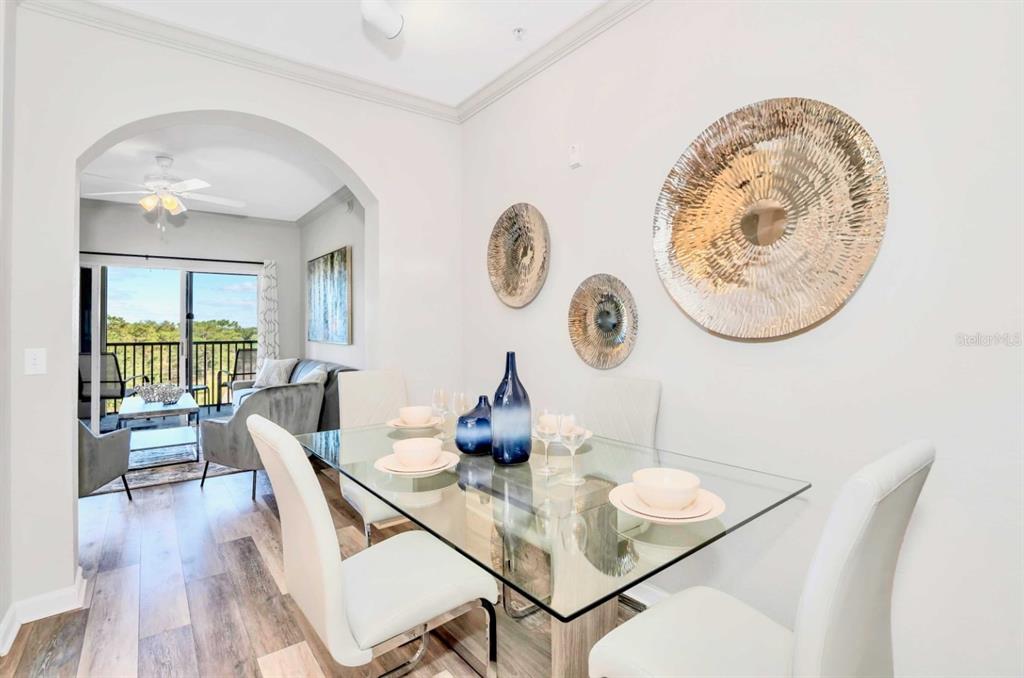 A dining area with a glass table and white chairs opens into a living room — 14200 AVALON ROAD UNIT 411, WINTER GARDEN, FL