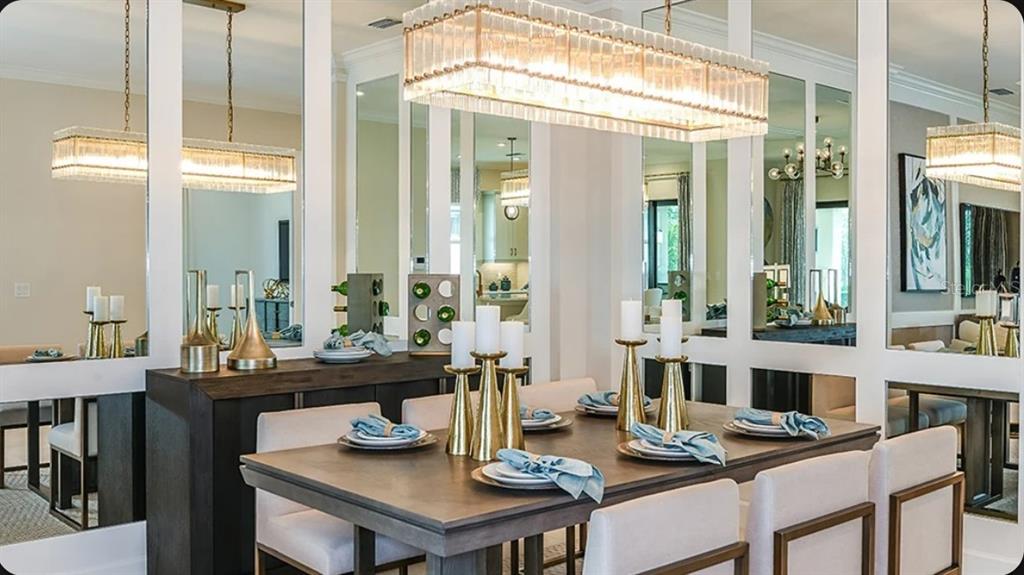 A dining room features a wooden table, upholstered chairs, a crystal chandelier, and mirrored walls — 3204 VICENZA COURT, BRADENTON, FL