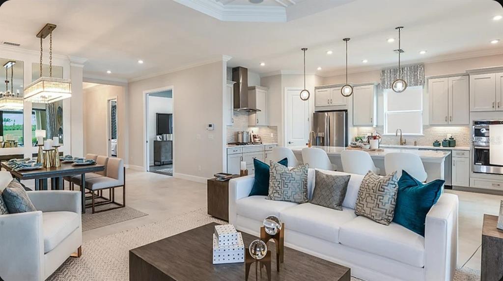 An open-concept living room and kitchen featuring white cabinetry, a kitchen island, and dining area — 3204 VICENZA COURT, BRADENTON, FL