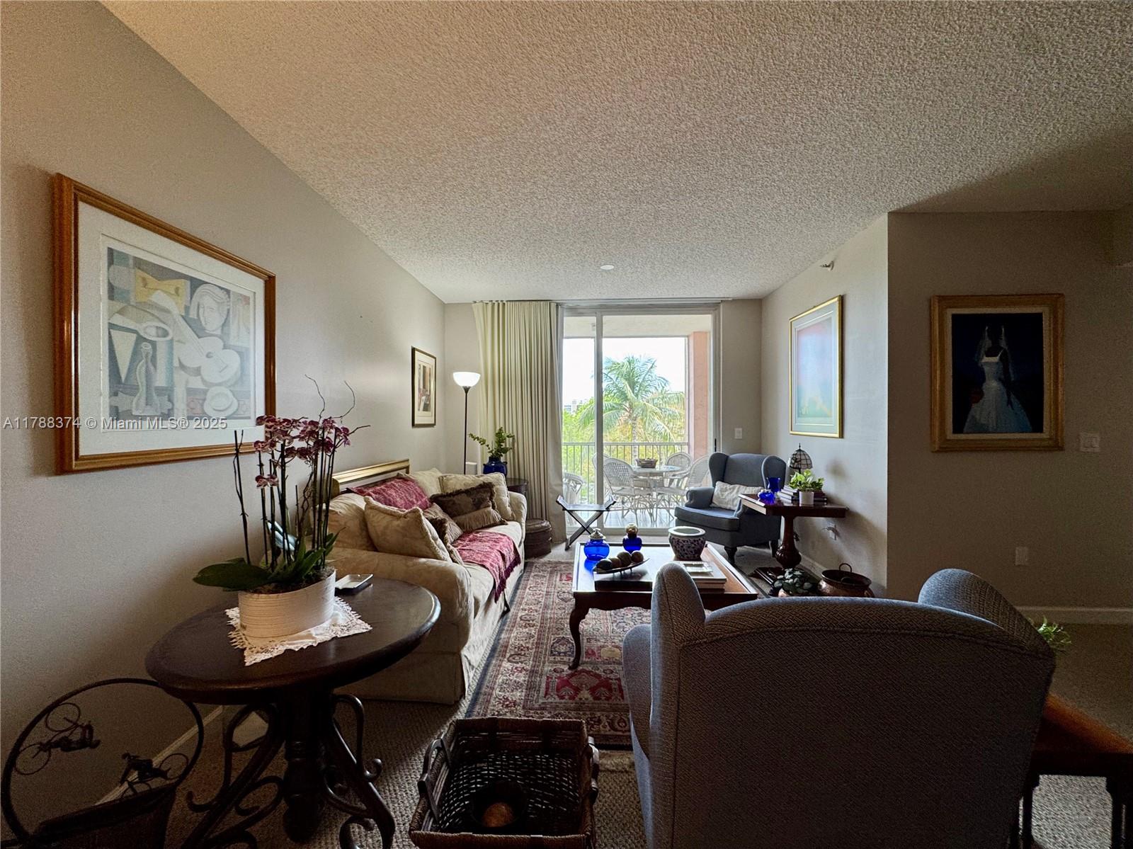 A living room features a sofa, armchairs, a coffee table, and a balcony with palm trees — 9805 NW 52nd St # 420, Doral FL 33178, DORAL, FL