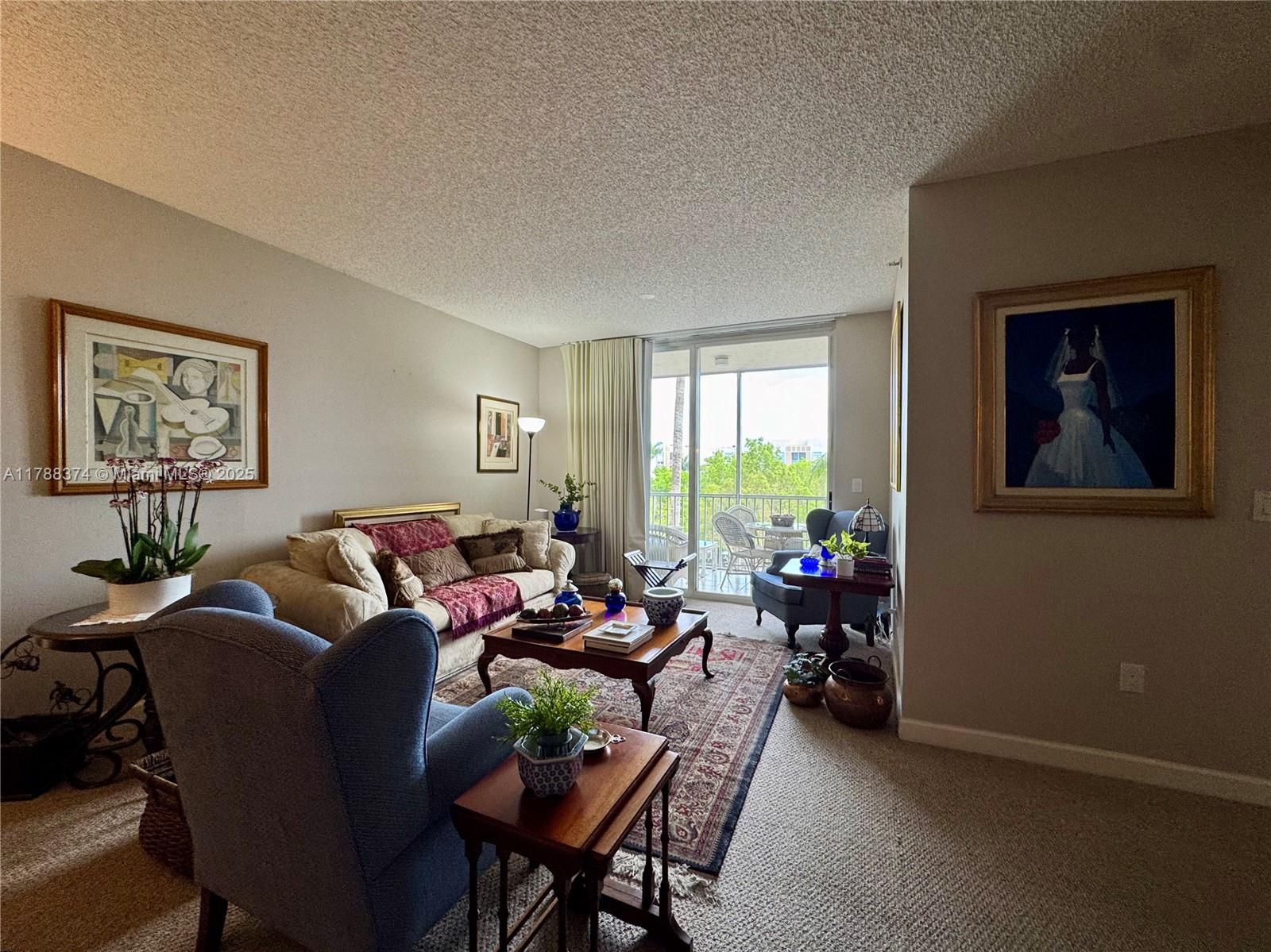A living room features a sofa, blue armchairs, a coffee table, and a balcony view — 9805 NW 52nd St # 420, Doral FL 33178, DORAL, FL
