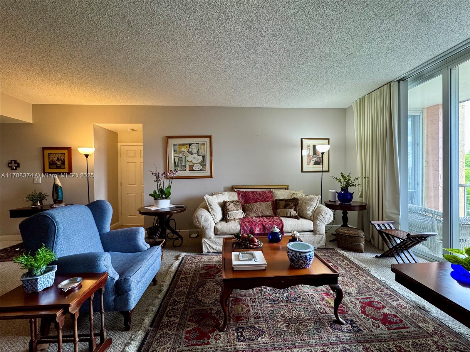 A living room features a blue armchair, a patterned area rug, and a beige sofa — 9805 NW 52nd St # 420, Doral FL 33178, DORAL, FL
