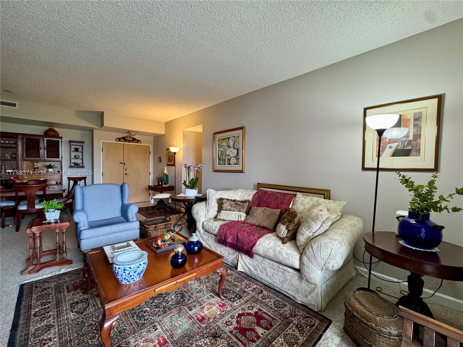 A living room features a patterned sofa, blue armchair, wooden coffee table, and area rug — 9805 NW 52nd St # 420, Doral FL 33178, DORAL, FL