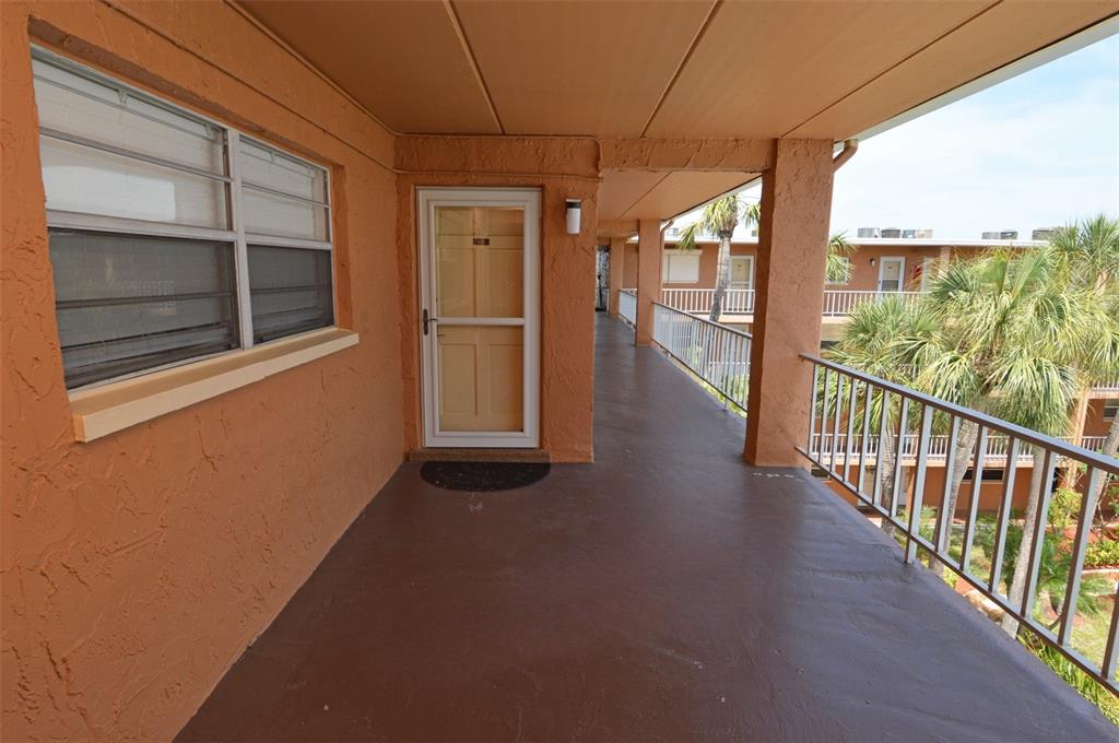 An outdoor walkway with a brown floor, orange walls, and a metal railing — 12760 INDIAN ROCKS ROAD UNIT 1110, LARGO, FL