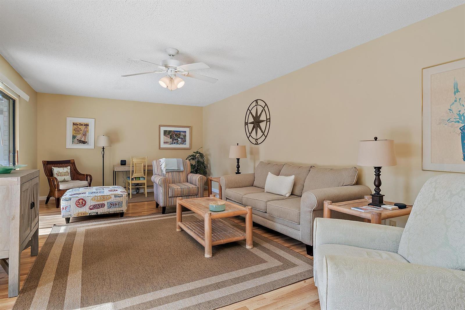 A living room with beige walls, a tan sofa, armchairs, and a wooden coffee table — 1420 Ocean Way # 28c, Jupiter FL 33477, JUPITER, FL