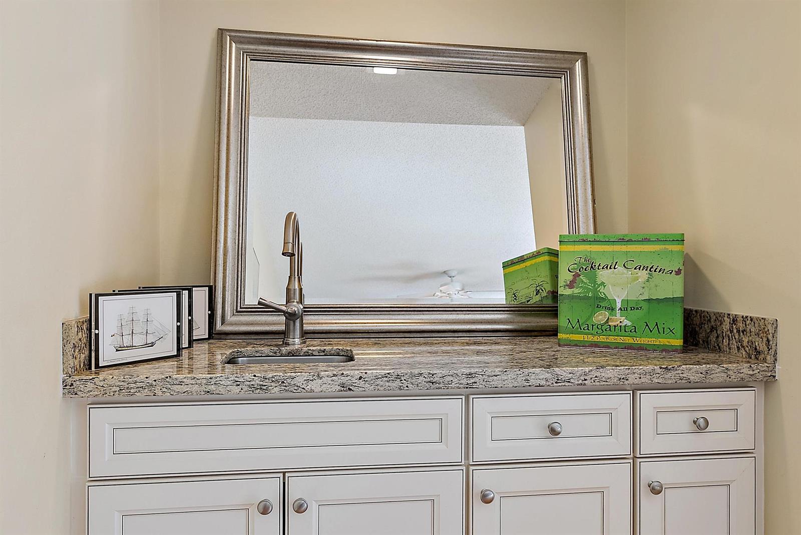 A wet bar features white cabinets, a granite countertop, a sink, and a large mirror — 1420 Ocean Way # 28c, Jupiter FL 33477, JUPITER, FL