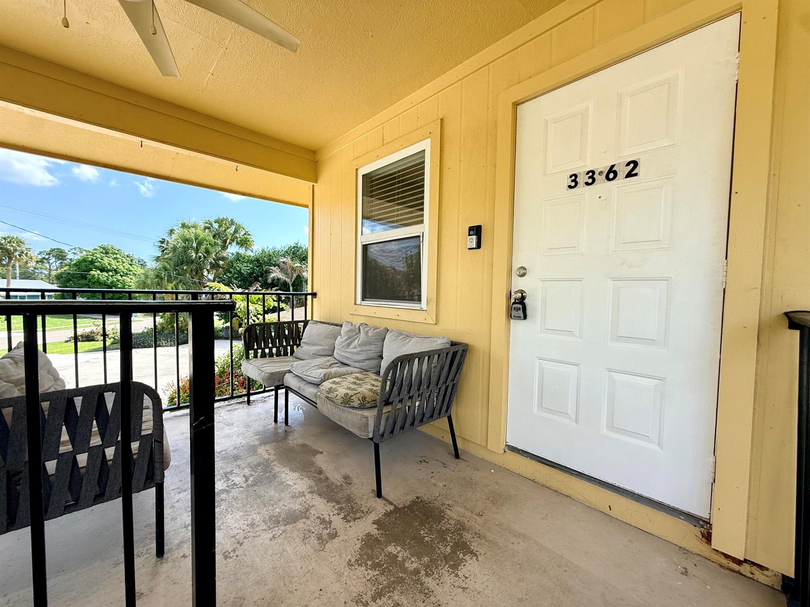 A covered porch features a gray sofa, a chair, and a white door with numbers — 3362 SE Jefferson Street, Stuart FL 34997, STUART, FL
