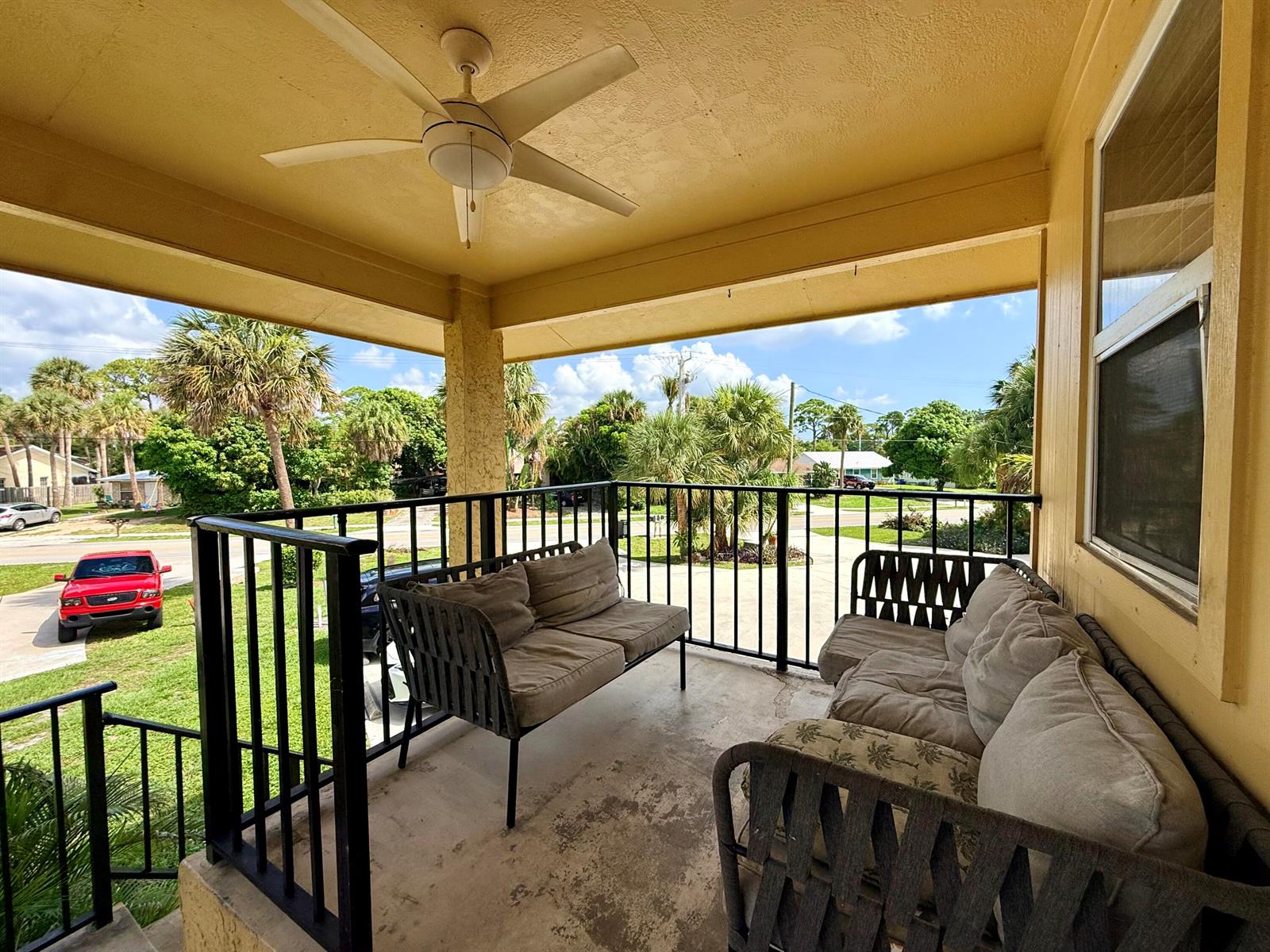 A covered porch features a ceiling fan, black metal railings, and two outdoor sofas — 3362 SE Jefferson Street, Stuart FL 34997, STUART, FL