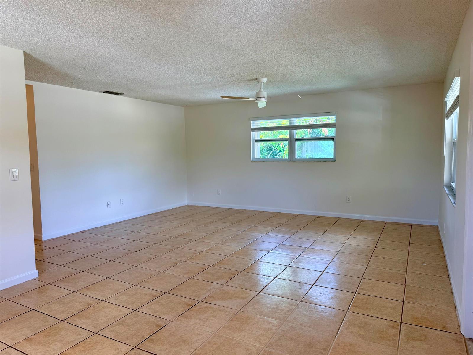 An empty room with beige tile flooring, white walls, a ceiling fan, and two windows — 3362 SE Jefferson Street, Stuart FL 34997, STUART, FL