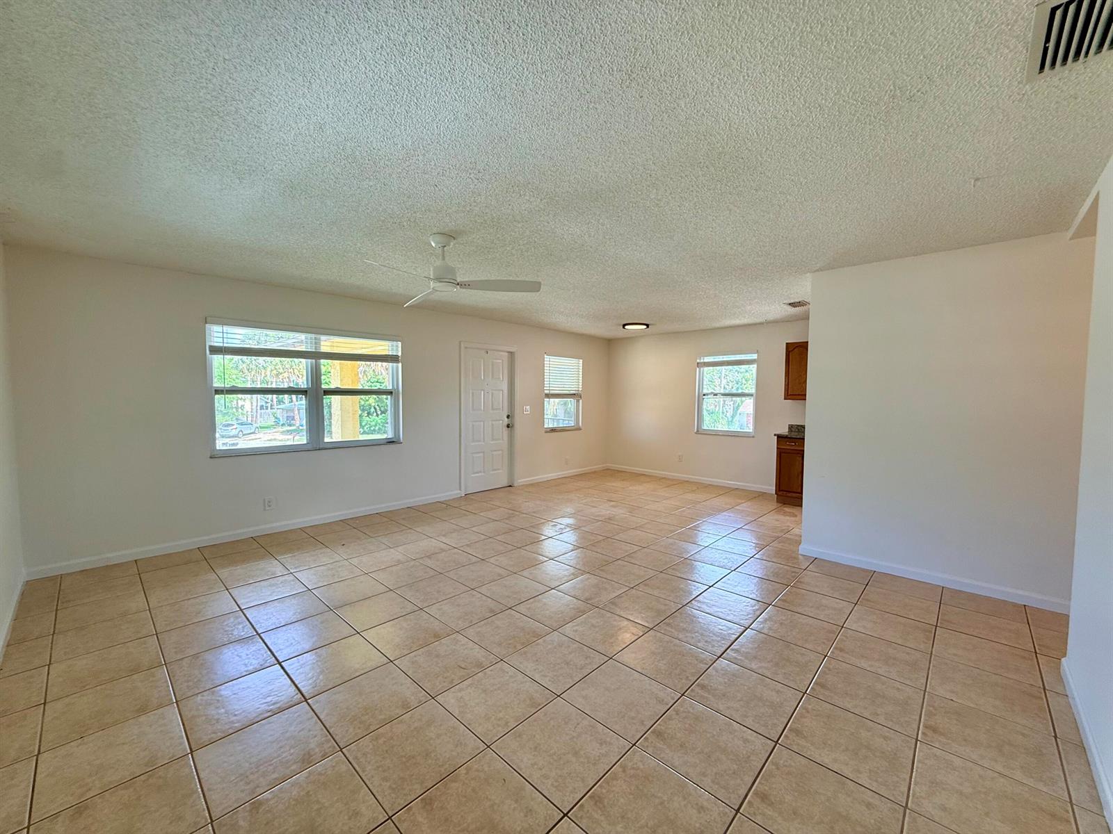 An open-concept living room features light-colored tile flooring, a ceiling fan, and white walls — 3362 SE Jefferson Street, Stuart FL 34997, STUART, FL