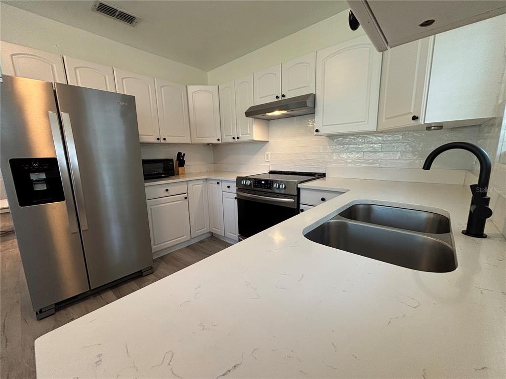 A kitchen features white cabinets, stainless steel appliances, and white countertops with a double sink — 1138 51ST AVENUE N, ST PETERSBURG, FL