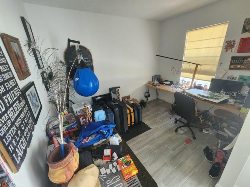 A home office features a desk, a punching bag, luggage, and tiled flooring — 1405 UNICE AVENUE N, LEHIGH ACRES, FL