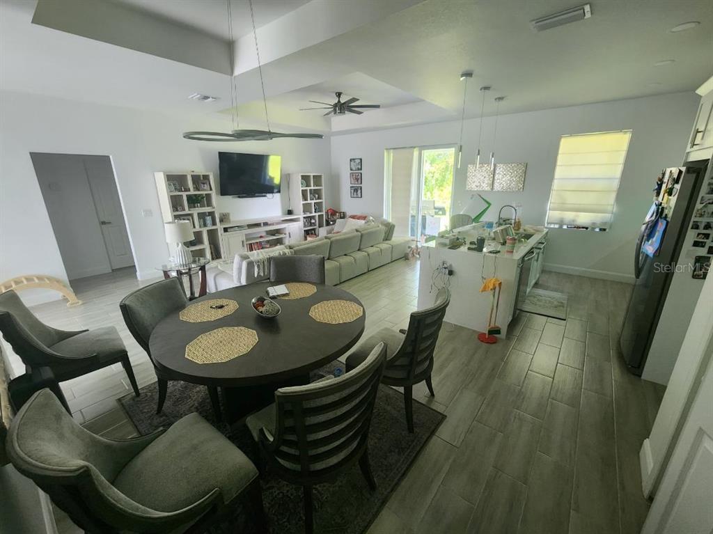 An open-concept living and dining area features tile flooring, a kitchen island, and modern furniture — 1405 UNICE AVENUE N, LEHIGH ACRES, FL