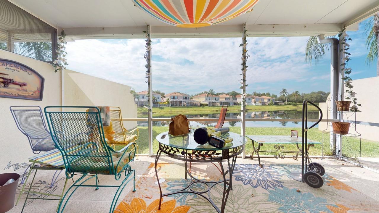 A screened-in patio overlooks a lake with residential houses in the background — 2136 Tigris Drive, West Palm Beach FL 33411, WEST PALM BEACH, FL