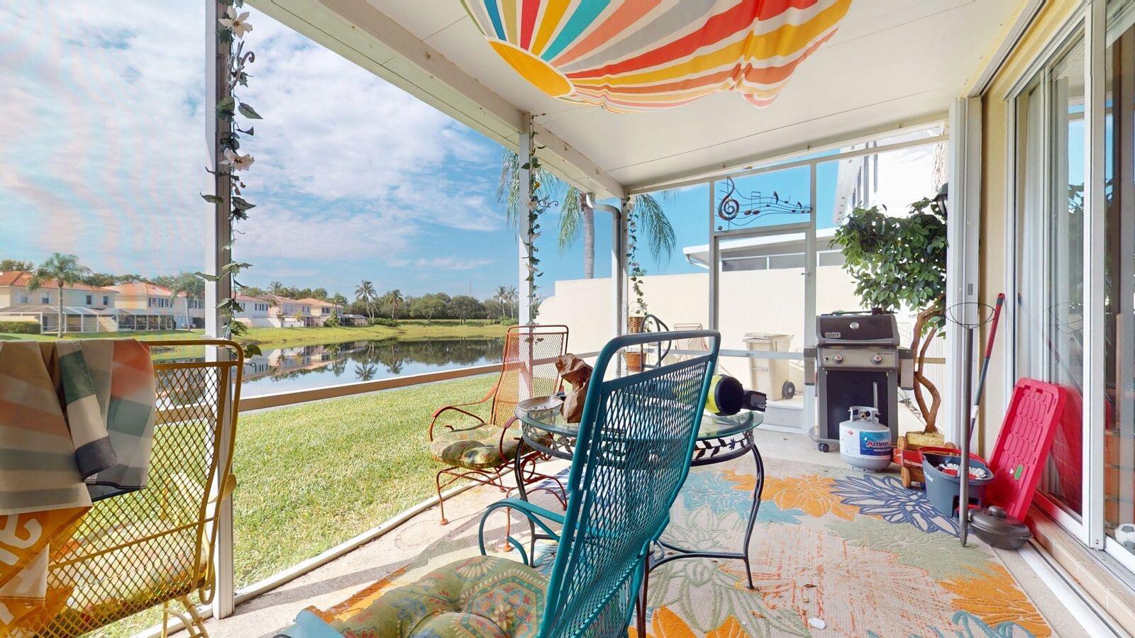 A screened-in patio with outdoor furniture, a grill, and a view of a lake — 2136 Tigris Drive, West Palm Beach FL 33411, WEST PALM BEACH, FL