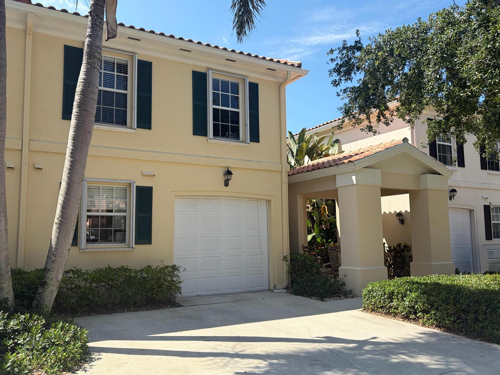 A two-story yellow stucco house with a garage, green shutters, and a covered entryway — 2136 Tigris Drive, West Palm Beach FL 33411, WEST PALM BEACH, FL