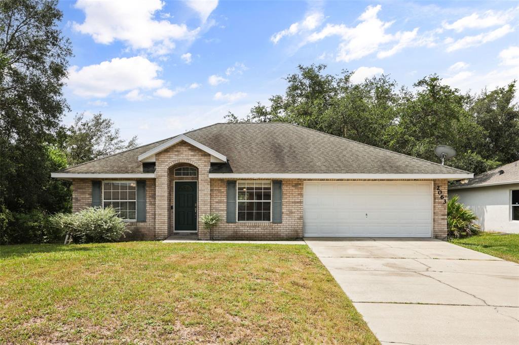 A single-story brick house with a two-car garage and a front lawn — 2063 MONTEREY DRIVE, DELTONA, FL