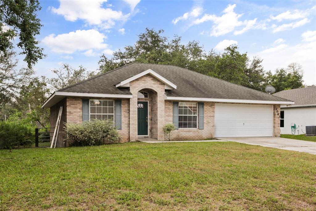 A single-story brick house with a dark green front door and a two-car garage — 2063 MONTEREY DRIVE, DELTONA, FL