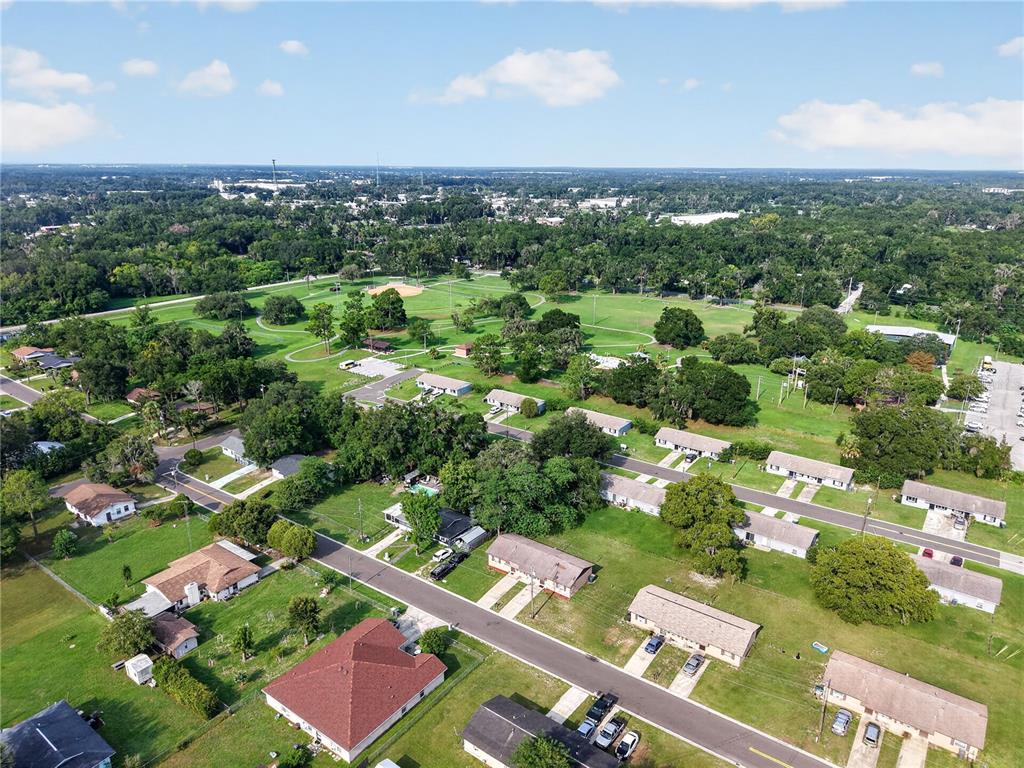 An aerial view shows a residential neighborhood with houses, streets, and a large park — 1632/1634 NW 20TH COURT, OCALA, FL
