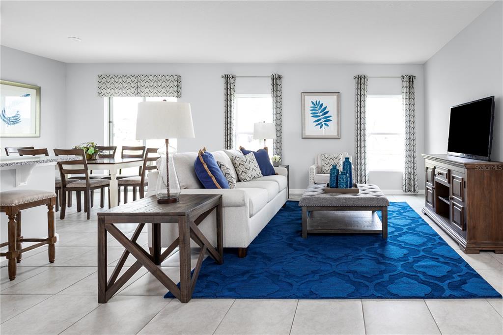 A living room and dining area feature tile floors, a blue rug, and neutral furniture — 6949 SUNDIAL DRIVE, LAKELAND, FL