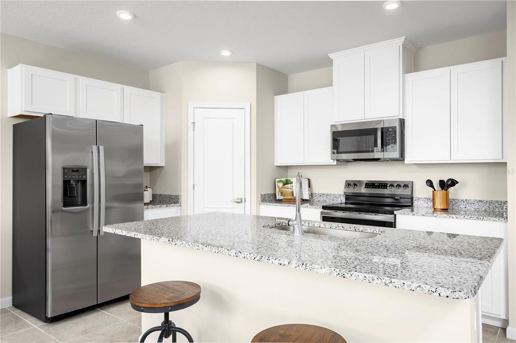 A kitchen with white cabinets, granite countertops, a center island, and stainless steel appliances — 6949 SUNDIAL DRIVE, LAKELAND, FL