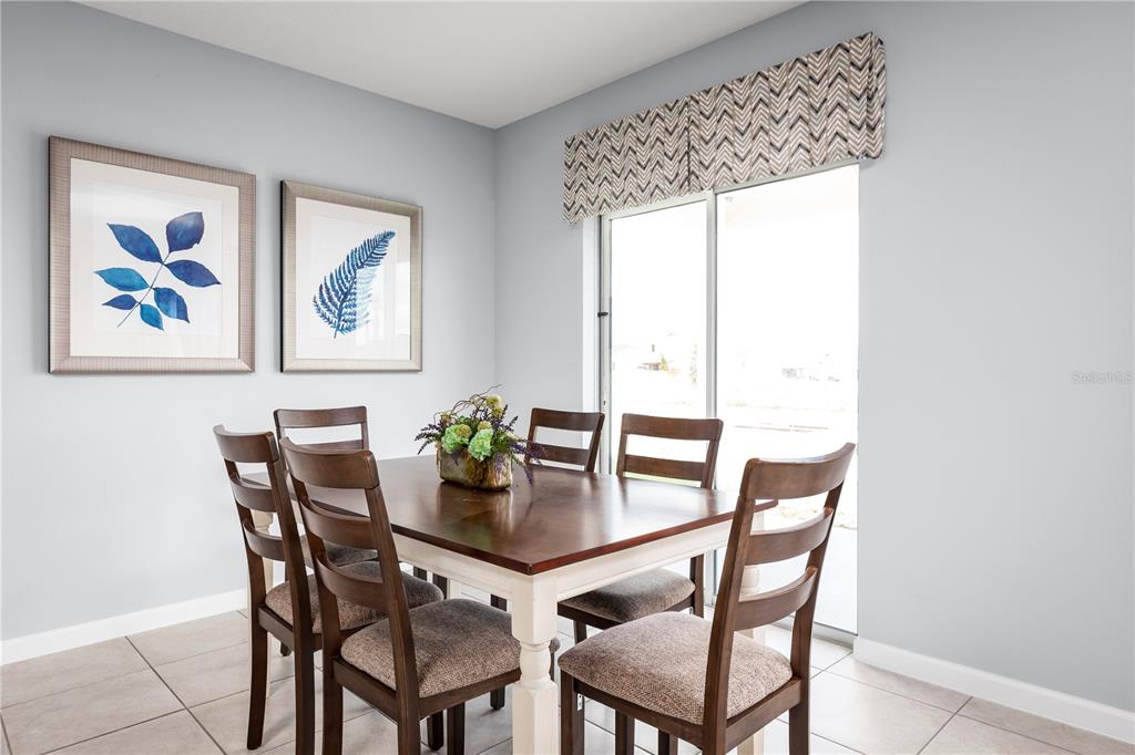 A dining area features a wooden table with four chairs, tiled floors, and wall art — 6949 SUNDIAL DRIVE, LAKELAND, FL