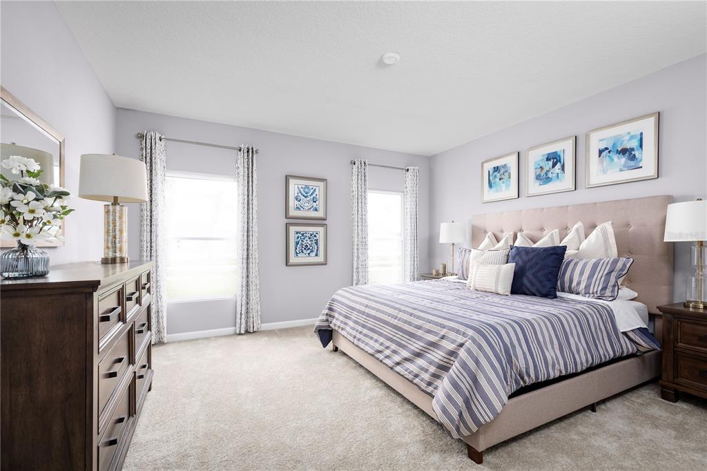 A bedroom features a king-sized bed with blue striped bedding, two windows, and wooden furniture — 6949 SUNDIAL DRIVE, LAKELAND, FL