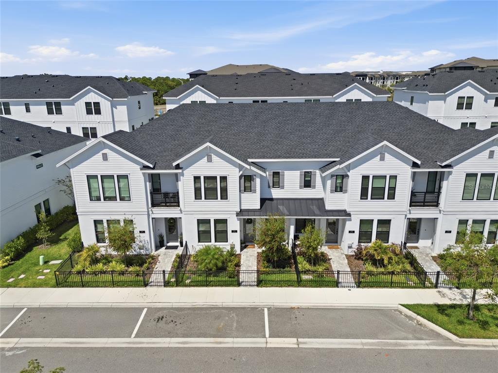 An aerial view of a row of modern white townhouses with dark shingled roofs — 7221 SUTTON LANE, SARASOTA, FL