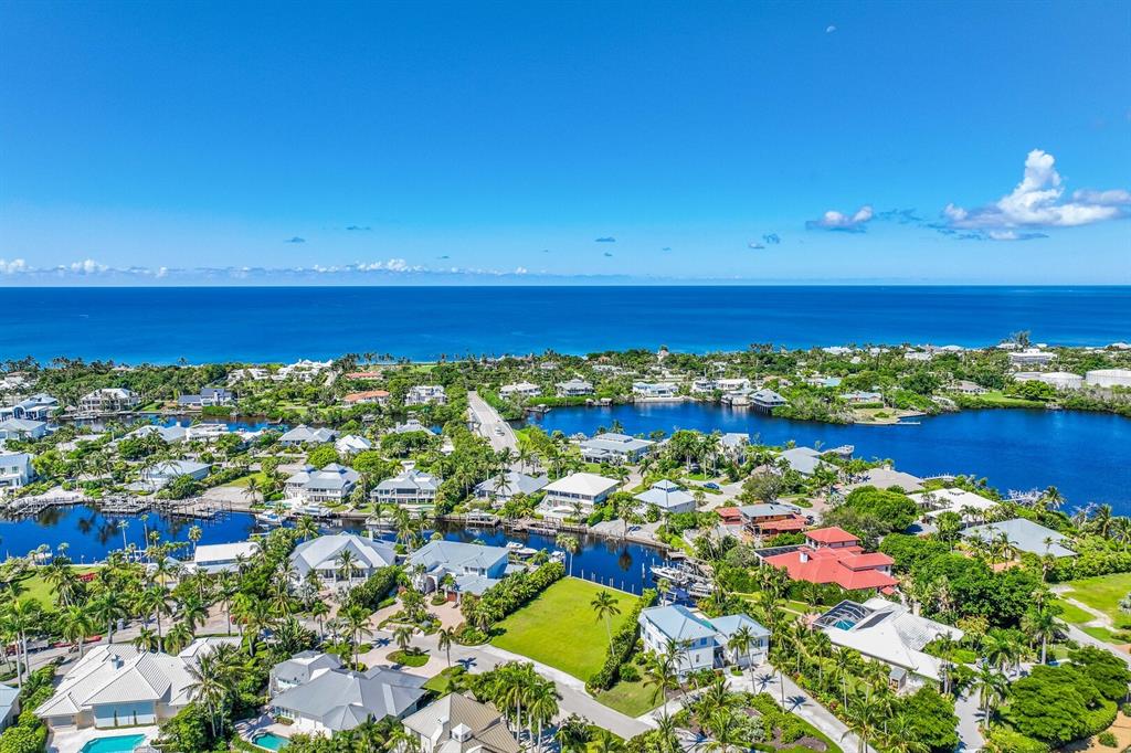 An aerial view shows a coastal neighborhood with houses, canals, and the ocean beyond — 1639 JEAN LAFITTE DRIVE, BOCA GRANDE, FL
