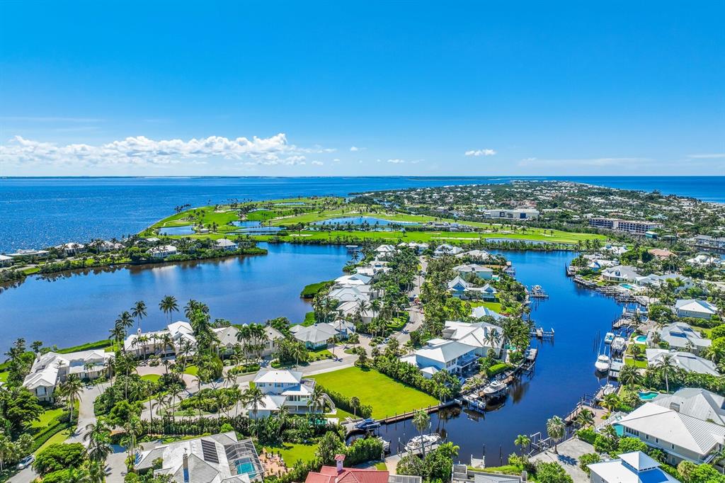 An aerial view shows a coastal neighborhood with houses, canals, and a golf course nearby — 1639 JEAN LAFITTE DRIVE, BOCA GRANDE, FL