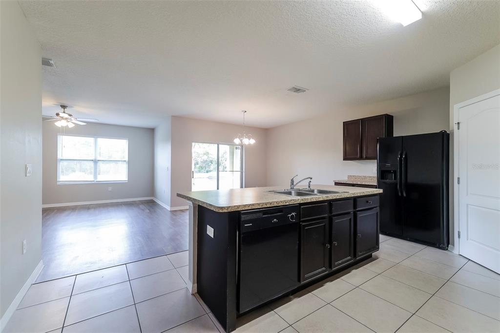 A kitchen with a dark island and black appliances opens to a living area — 2330 SEQUOIA WAY, DAVENPORT, FL